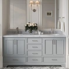 a bathroom with double sinks and marble counter tops in grey tones, surrounded by white walls