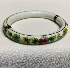 This is such a pretty and unique vintage bracelet, made of white porcelain with green leaves and multi coloured flowers outlined with gold. Brass hinge and box clasp. Measures approximately 7 inches. Definitely, one of a kind.