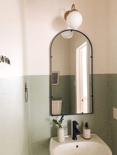 a white sink sitting under a bathroom mirror next to a light above it's faucet