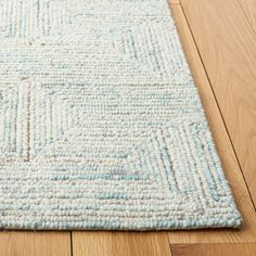 a light blue and white rug on the floor with wood floors in the foreground