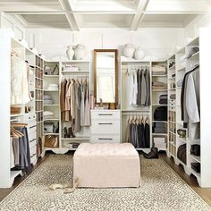 a walk in closet filled with lots of clothes and shoes on top of white shelves