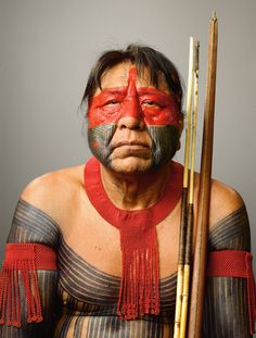 a man with painted face holding a stick and wearing red, white and grey makeup