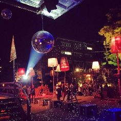 a disco ball is suspended from the ceiling in front of a crowd at night time