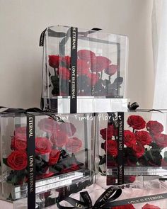 three clear boxes with red roses in them