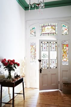 a white door with stained glass windows and a table on the floor in front of it