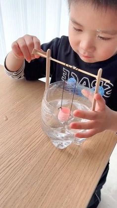 a young boy is playing with an object made out of popsicle sticks and water