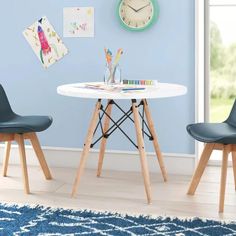 a white table with two chairs and a clock on the wall behind it in a blue room