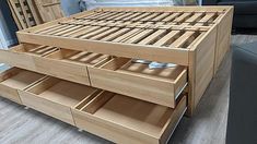 a wooden bed frame with drawers on the bottom