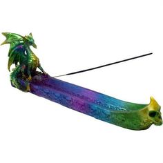 No matter what kind of incense you enjoy, you should have a way to burn it. Add the Multicolor Dragon Incense Burner to your home or office decor. Made from cold cast resin, this hand-painted incense burner can hold one stick of incense, not included. A green dragon sits on one end of the incense burner. Multicolored highlights adorn the dragon. They match the purple, blue, and green incense tray. Along the sides of the tray are skull designs. A knotwork pattern adorns the inside of the tray. Fi Multicolored Highlights, Incense Tray, Dragon Incense Burner, Skull Designs, Fantasy Gifts, Green Dragon, Skull Design, Incense Burner, Golden Color