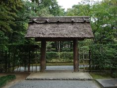 a small wooden structure in the middle of a forest with trees and bushes around it