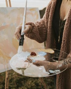 a woman is painting on an easel with her hands