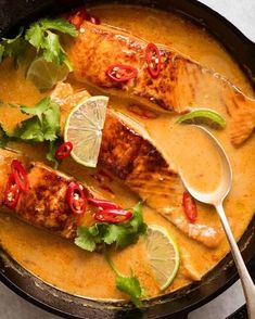 two fish fillets in a skillet with garnishes and limes