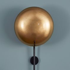 a gold ball mounted to the side of a wall next to a black pole with a light on it