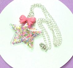 Here we have a lovely Star & Bow Shaker Necklace which is made on lovely silver plated chain to a length of 51cms (20 inches) although you can choose different lengths from the drop down menu.   This delightful Kawaii Necklace is made with a PVC Shaker Star Pendant which measures 7 x 7 cm and has a 3 x 2cm Pink Acrylic Bow on top that is full of sequins .  This Fairy Kei Necklace closes with a lobster clasp.  A great gift for someone special and will arrive gift wrapped. I also have a matching p Silver Star Charm Necklaces For Party, Silver Star-shaped Charm Necklaces For Party, Whimsical Silver Charm Necklace For Birthday, Party Star Charm Necklaces, Cute Silver Charm Necklaces For Party, Whimsical Silver Necklaces For Party, Whimsical Silver Necklace For Party, Kawaii Silver Handmade Necklaces, Handmade Silver Kawaii Necklaces