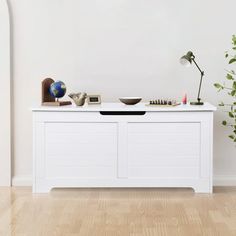 a white cabinet with a bowl on top next to a potted plant and other items