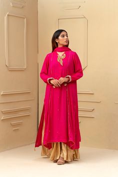 This bright pink and gold wide leg shalwar kameez features a stunning shocking pink chiffon fabric with intricate mukesh chhan detailing all over the shirt and dupatta. With tikka work leaves adorning the neck, this ensemble exudes elegance and sophistication, perfect for any special occasion. 3-Piece Suit Pink Georgette Palazzo Set With Sheer Dupatta, Pink Raw Silk Sharara With Dabka Work, Pink Georgette Palazzo Set With Mirror Work, Pink Raw Silk Palazzo Set With Straight Kurta, Pink Palazzo Set With Zari Work For Festive Occasions, Pink Palazzo Set With Zari Work For Festive, Pink Palazzo Set With Dabka For Festive Occasions, Festive Pink Palazzo Set With Zari Work, Pink Resham Embroidery Palazzo Set In Raw Silk