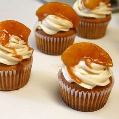 several cupcakes with icing and caramel toppings on a white surface