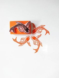 an orange rubber stamp with two fish on it's side and one in the shape of a rectangle