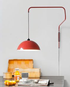 a red lamp sitting on top of a table next to oranges and a cutting board