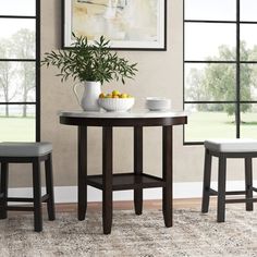 a small table with two stools and a bowl of fruit on the table next to it