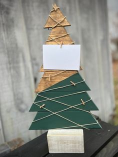 a christmas tree made out of wood and paper on top of a piece of wood