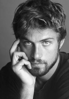 a black and white photo of a man holding his hand to his face while looking at the camera