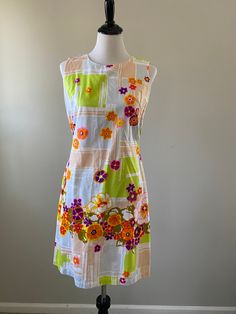 1960s-70s vibrant floral Longe Craft shift dress. The perfect dress for summer vacation! The cotton dress has pops of purple, hot pink, orange, olive green, and yellow flowers set against a beige, light blue, and lime green geometric background. Perfect for the beach, lounging around the house, or summer weekend fun. The dress zips up the back and has pockets. The cotton is sheer. Union made in the USA. Condition: Excellent vintage condition. Measurements: Size: small. Measurements taken when ga Retro Print Summer Dresses For Spring, Mod Summer Beach Dresses, Summer Mod Beach Dresses, Lined Mod Summer Dresses, 1970s A-line Summer Dress, Summer Multicolor Mod Dresses, Cotton Dresses With Retro Print For Summer, Multicolor Mod Summer Dress, Multicolor Mod Style Summer Dresses