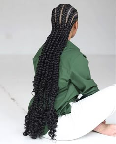 a woman sitting on the floor with her long hair in braids and wearing a green shirt