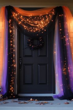 the front door is decorated with purple and orange tulle curtains, pumpkins and wreath