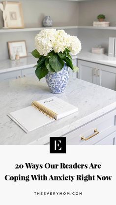 a blue and white vase filled with flowers on top of a kitchen counter next to a notepad