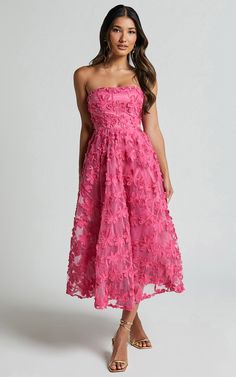 a woman is wearing a pink dress with flowers on it