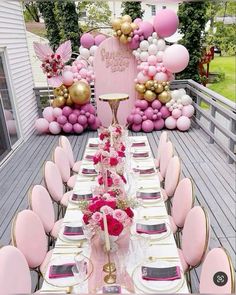 a table set up for a party with balloons and flowers on the top, along with pink chairs