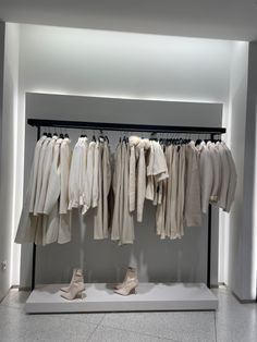 there are several pairs of shoes hanging on the rail in front of some shirts and pants