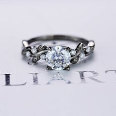 an engagement ring with leaves on the band and a round diamond center stone in the middle