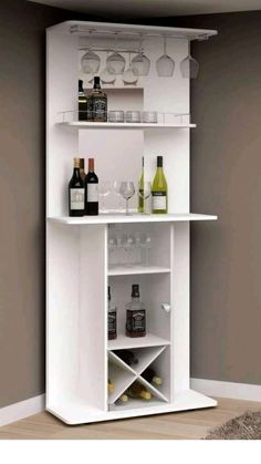 a white shelf with wine glasses and bottles on it in front of a gray wall