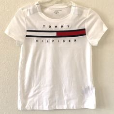 Nwot Tommy Hilfiger Big Girl's Adaptive T-Shirt Short Sleeve. This T-Shirt Is Perfect For Girls Who Love Casual And Comfortable Clothing. Made Of 100% Cotton And Featuring A Crew Neck With Pullover Closure, This Shirt Is Breathable And Stretchy, Making It Ideal For Summer, Fall, And Spring Seasons. It Comes In White With A Solid Pattern, Logo Accent, Machine Washable, Made In India. Pullover, With Hook And Loop Closure Please Verify With Measures Run Small M Shoulder To Shoulder 12” Armpit To Ar Tommy Hilfiger Cotton Tops With Logo Print, Tommy Hilfiger Graphic Tee With Letter Print, Tommy Hilfiger Graphic Tee With Graphic Print, Trendy Tommy Hilfiger Tops With Graphic Print, Tommy Hilfiger Graphic Print Short Sleeve Shirt, Tommy Hilfiger Graphic Print Tee, Tommy Hilfiger Short Sleeve Top With Letter Print, Tommy Hilfiger Graphic Tee For Spring, White Cotton Tommy Hilfiger T-shirt