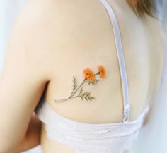 an orange flower tattoo on the back of a woman's shoulder