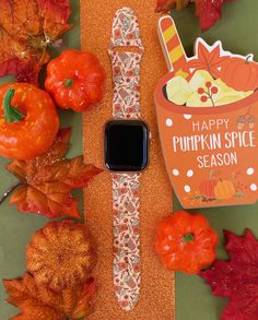 an apple watch sitting on top of a table next to autumn leaves and pumpkins