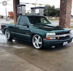 a green truck parked in front of a gas station