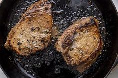 two steaks cooking in a skillet on the stove