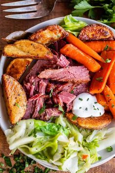 corned beef with carrots, potatoes and lettuce on a white plate