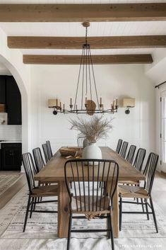 the dining room table is surrounded by black chairs and wooden beams, along with an antique chandelier