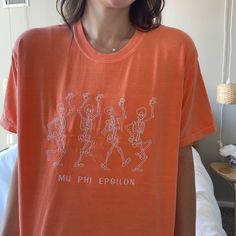 This cute tee is sure to make it beyond just the halloween season, it's so cute you wont want to take it off! Coming in many tee colors, the dancing skeletons are embroidered above your choice of optional text; add your sorority, or anything else you would like! No additional cost for wording underneath the skeletons, the thread color will be the thread color for both the skeletons and the optional text. Tee shown in melon with white thread. Colors: Thread Color: Casual Embroidered Halloween T-shirt, Halloween Cotton Top With Embroidered Graphics, Dancing Skeletons, Dancing Skeleton, Text Tee, The Skeleton, Skeleton Halloween, Thread Colors, Comfort Colors Tee