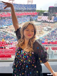 a woman standing in front of a stadium filled with people