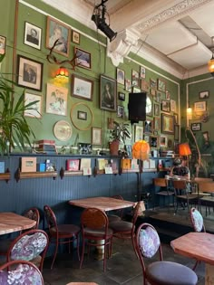 the interior of a restaurant with tables, chairs and pictures on the wall above them