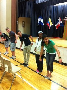 several young people are standing on the edge of a wooden floor in front of an audience