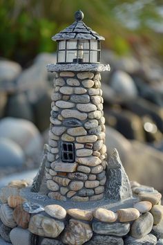 a small lighthouse made out of rocks with a light on it's top sitting on the beach