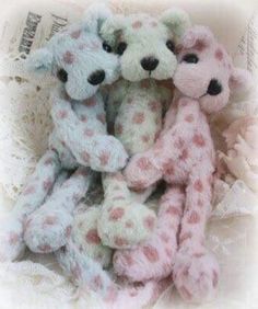 three teddy bears are sitting together in a pile, one is pink and the other is white