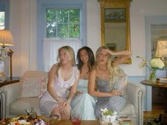 three women sitting on a couch in front of a table full of food and drinks