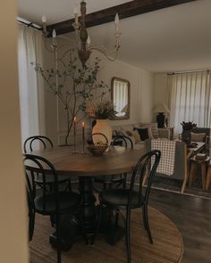 a dining room table with chairs and a vase filled with flowers sitting on top of it